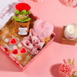 Load image into Gallery viewer, Valentine's Day gift box with a small plant, heart-shaped items, and a candle on a pink background.
