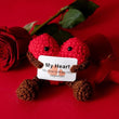 Load image into Gallery viewer, Crocheted heart-shaped plush toy with a message card on a red background
